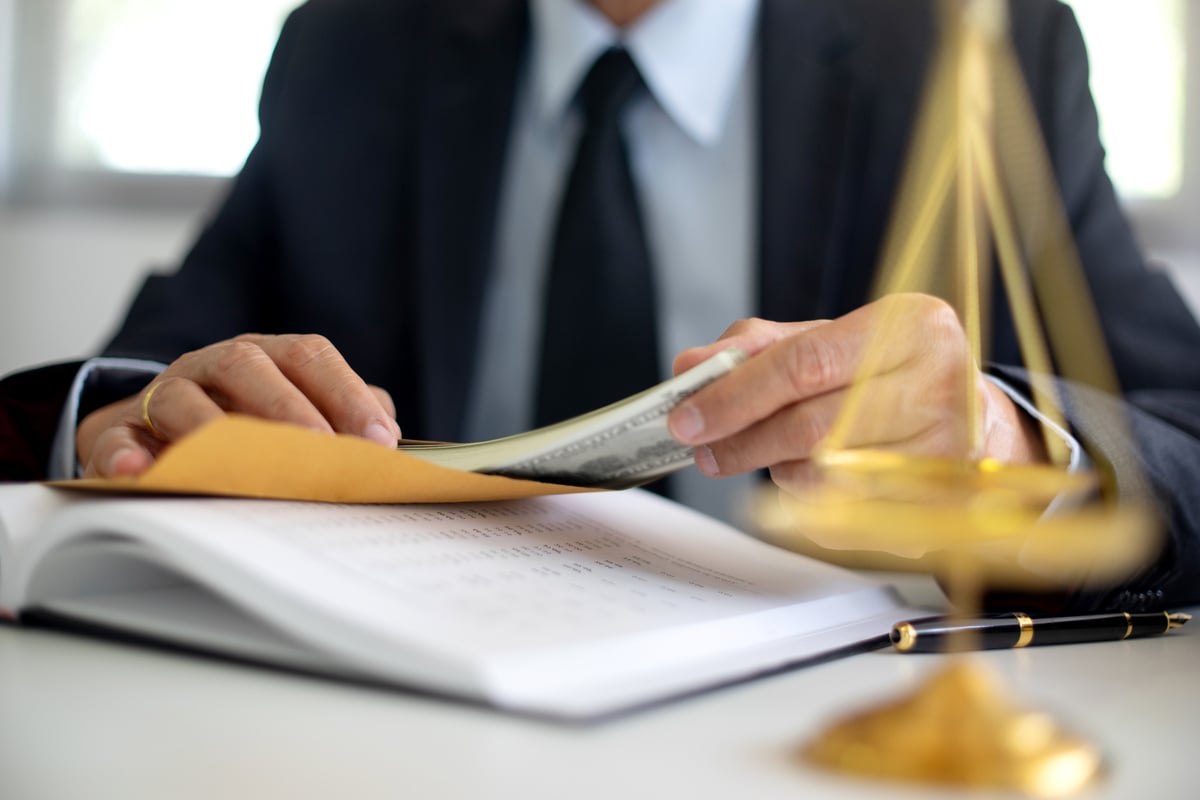 Person in Suit Putting Money in Envelope 