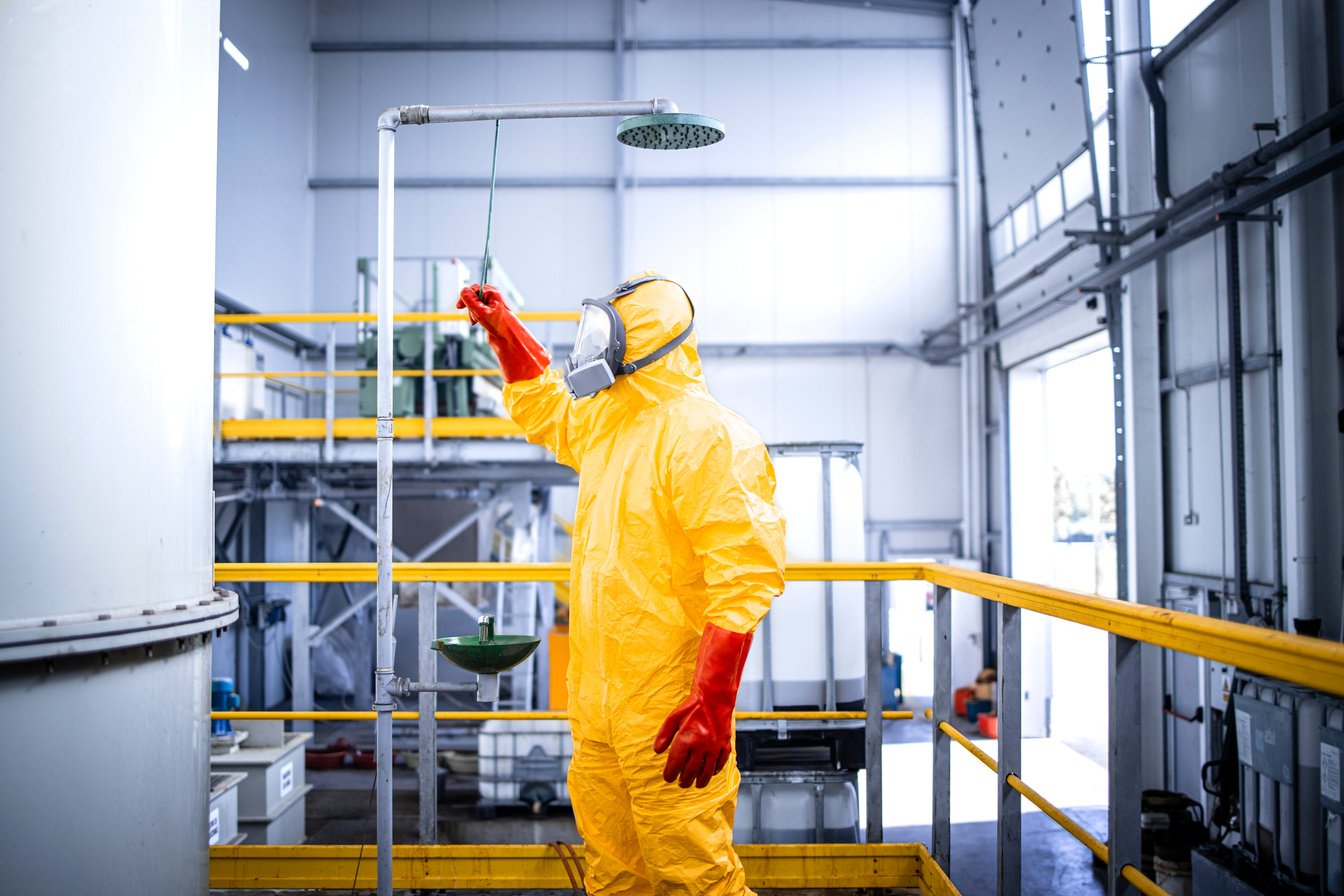 Safety at work. Occupational health and safety regulations. Worker in chemicals production plant taking a shower after accident washing away the acid.